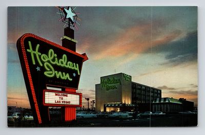 Saturated vintage Curteich postcard of the Holiday Inn at dusk: orange arrow-shaped sign with neon starburst and Welcome to Las Vegas marquee, white six-story hotel with green Holiday Inn script, peach and lavender sunset clouds.