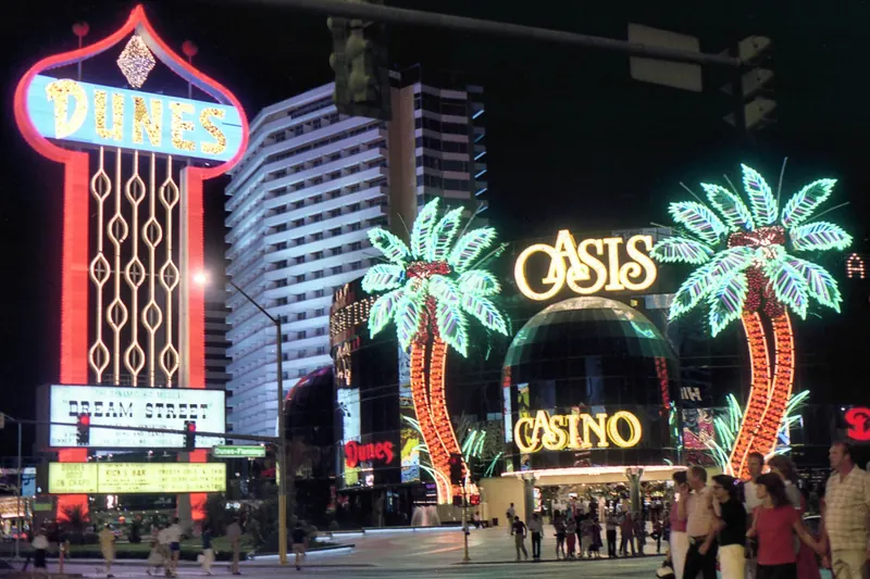 The Dunes hotel sign glowing in orange and gold neon at night in 1983.