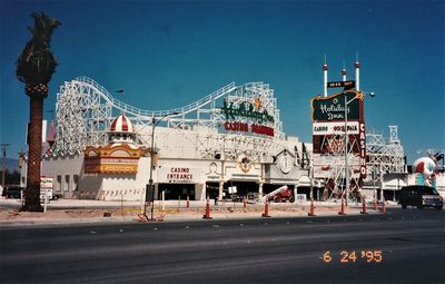 The Boardwalk facade under construction in 1995: white roller coaster framework partly unfinished, Holiday Inn Casino Boardwalk neon signage, an older freestanding Holiday Inn sign, traffic cones and dirt in the foreground, orange film date stamp reading 6 24 95.