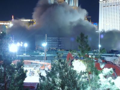 The same view moments after the implosion: the tower is gone, replaced by a huge gray dust cloud spreading between the neighboring hotels under the night sky.