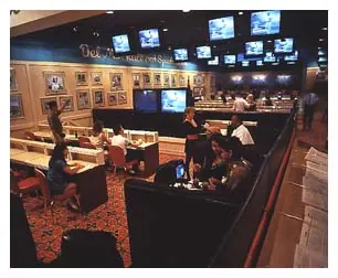 Tiny 1997 website photograph of the Del Mar Race and Sports Book, with television screens, tiered booths and pink neon.