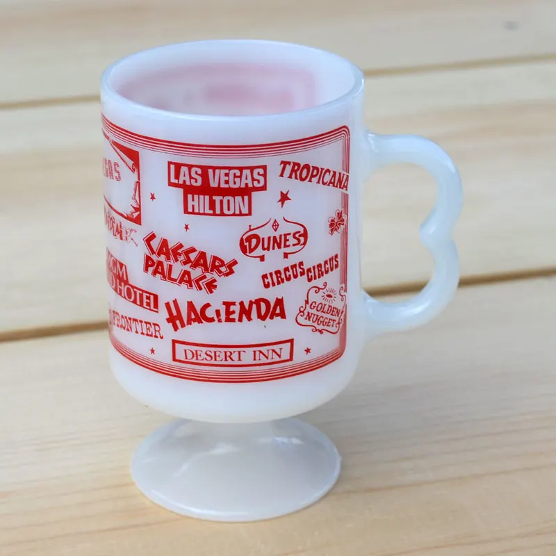 Vintage milk-glass pedestal mug printed with the names and signs of old Las Vegas casinos.