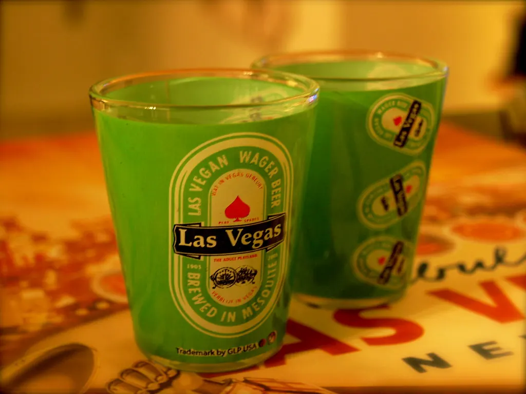 Pair of green Las Vegas souvenir shot glasses with western wagon artwork.