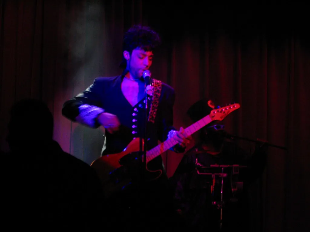 A Prince tribute performer from Purple Reign sings and plays guitar on the small Lighthouse Lounge stage in October 2005, lit in red and violet.
