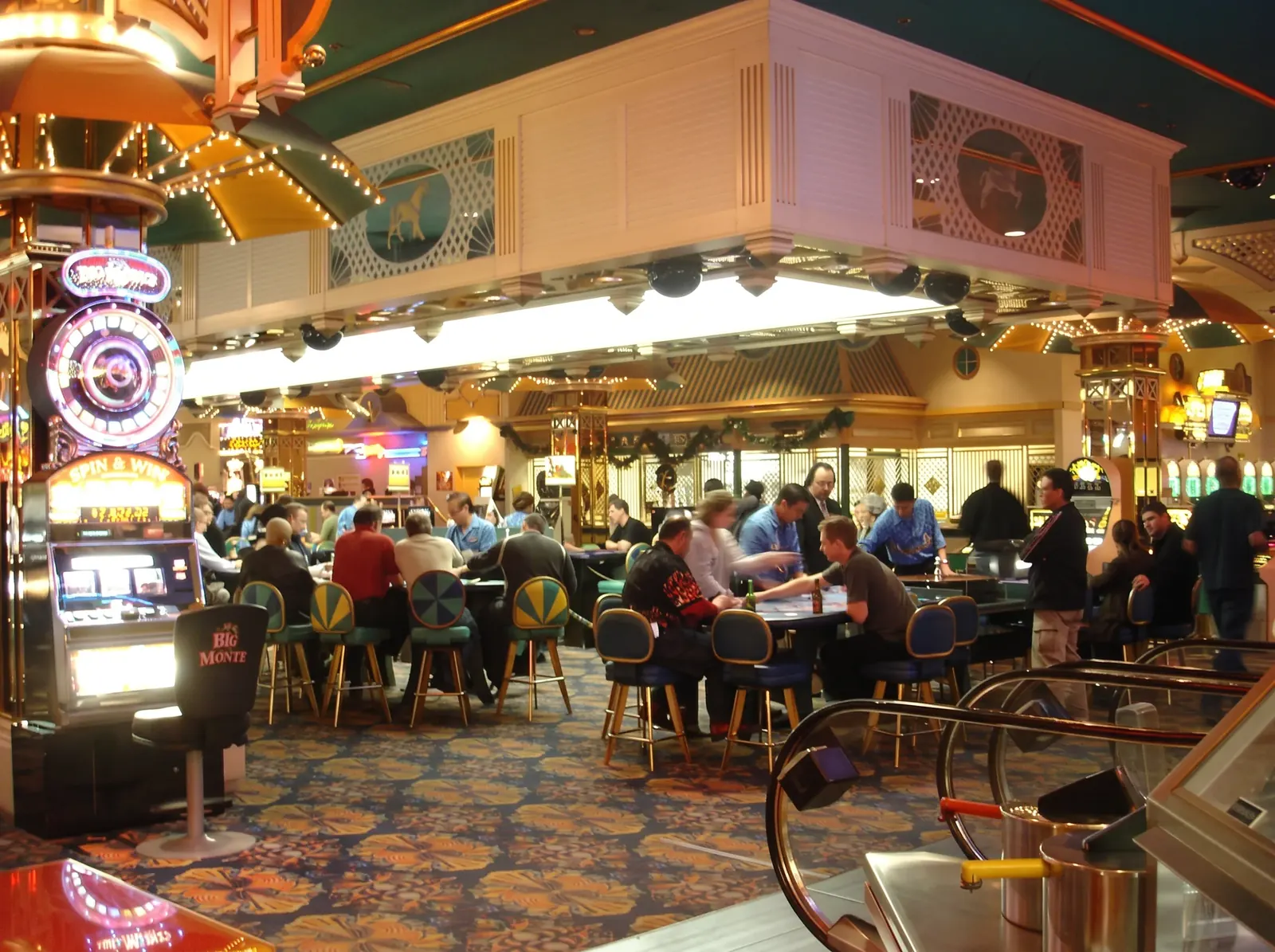 A busy Boardwalk casino pit in 2006 beneath a carousel-style pavilion, with players filling the tables and slot machines glowing nearby.