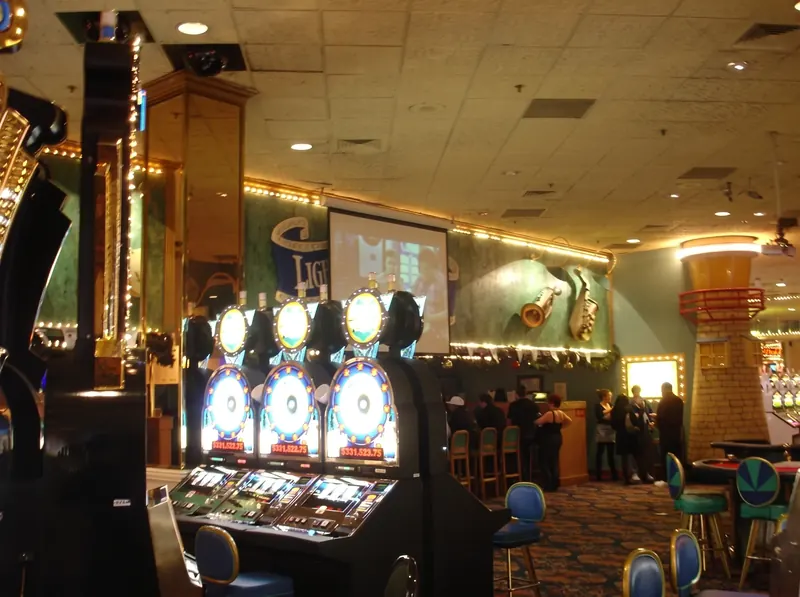 Boardwalk slot machines glowing near the casino bar, with oversized saxophone and music-note wall decorations beyond.