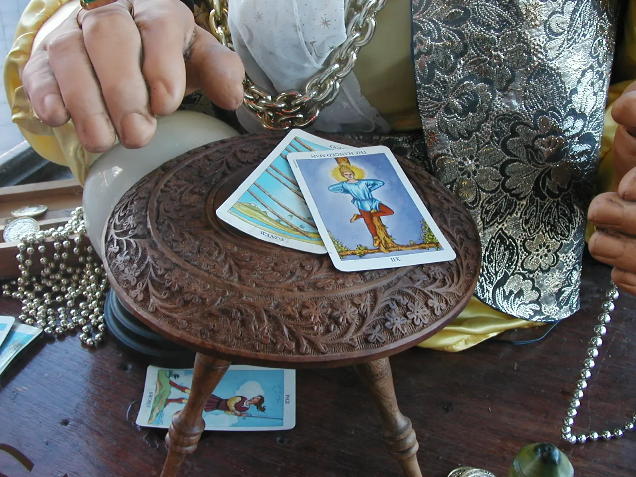 Zoltar's hands above tarot cards on a carved wooden table at the Boardwalk.